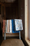 Stack of patterned fabric samples on a chair indoors